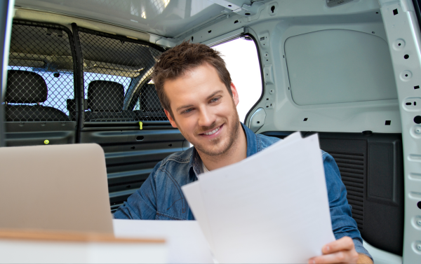 A pet groomer reviewing an insurance policy in their mobile van.